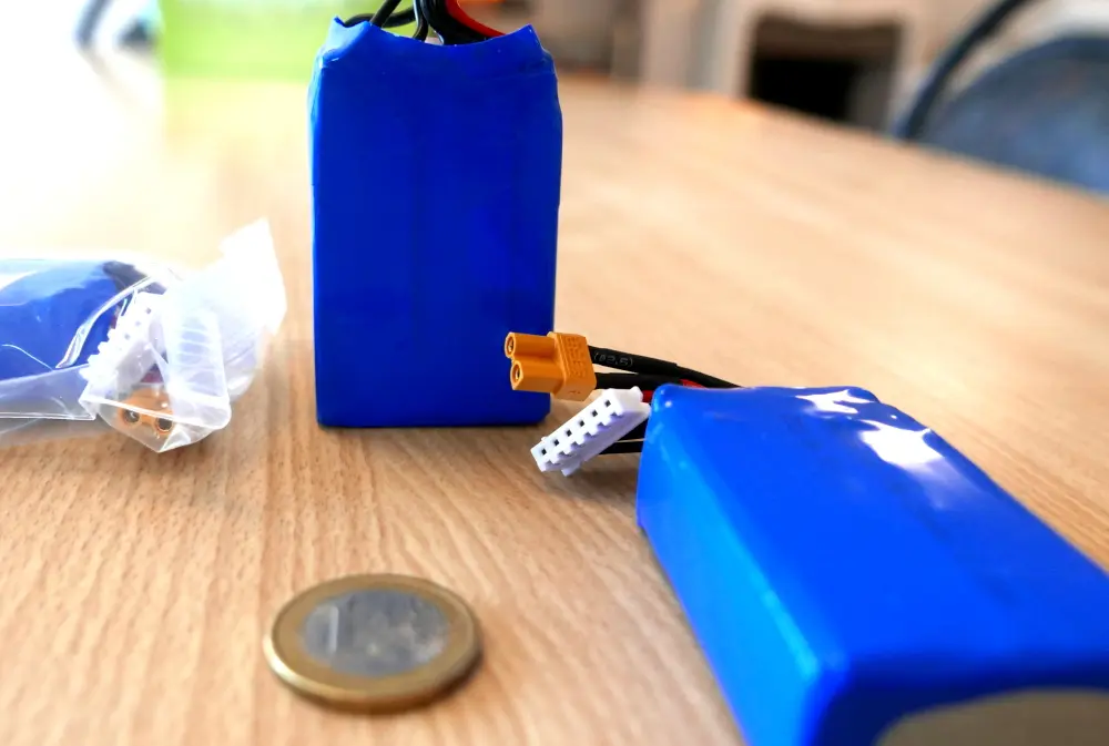 Deux batteries à côté d&#39;une pièce de un euro, montrant leur taille et leurs connecteurs.